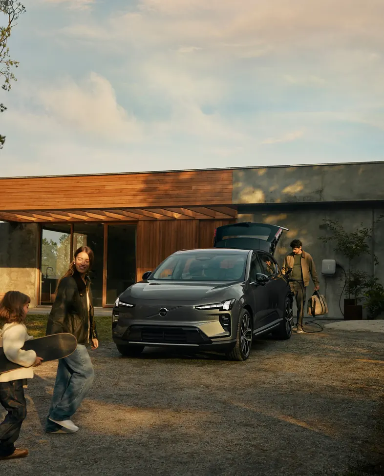 Família chegando em casa com um Volvo estacionado na entrada
